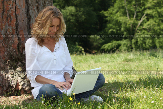 Woman laughing at her laptop computer in the park. Стоковое фото, агентство Ingram Publishing / Фотобанк Лори