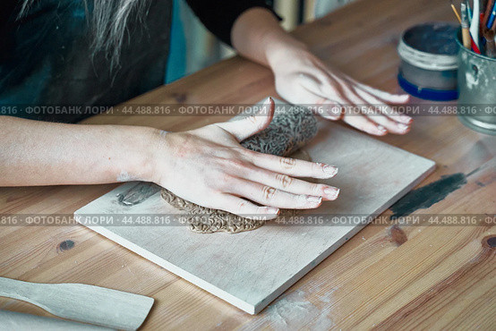 Woman making pattern on ceramic plate, hands close-up, focus on palms. Стоковое фото, фотограф Natalia Gdovskaia / Фотобанк Лори