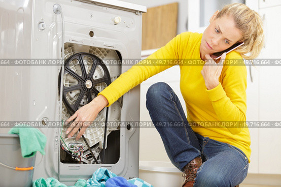 woman mopping up leaking sink on phone to plumber. Стоковое фото, агентство Ingram Publishing / Фотобанк Лори