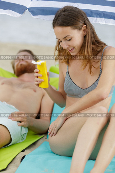woman on beach applying suncream. Стоковое фото, агентство Ingram Publishing / Фотобанк Лори