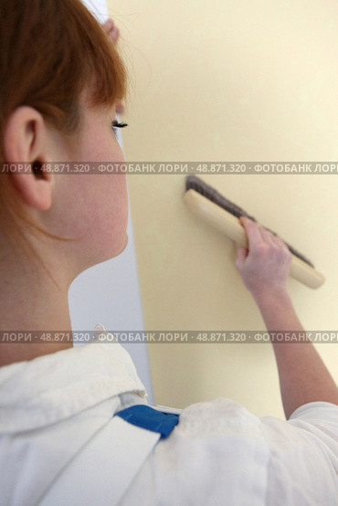 Woman passing brush over wall paper. Стоковое фото, агентство Ingram Publishing / Фотобанк Лори