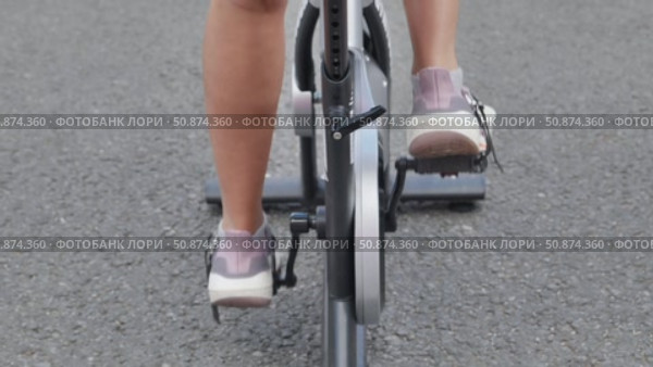 Woman pedaling on stationary bicycle during sports day. Стоковое видео, видеограф Mikhail Davidovich / Фотобанк Лори
