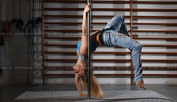 Woman practicing pole dancing in dark studio. Стоковое фото, фотограф Яков Филимонов / Фотобанк Лори