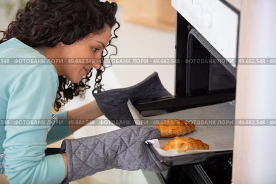 woman putting plate with croissants in microwave indoors. Стоковое фото, агентство Ingram Publishing / Фотобанк Лори