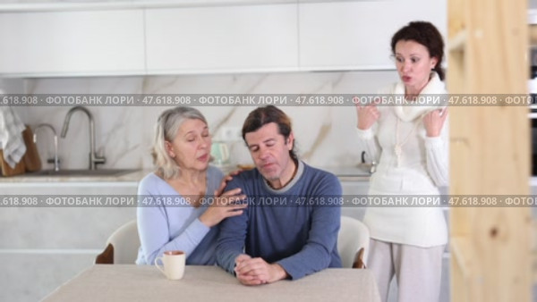 Woman scolding man at kitchen while old woman calming him down. Стоковое видео, видеограф Яков Филимонов / Фотобанк Лори