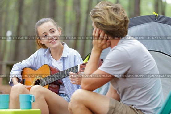 woman singing to boyfriend in a camp site. Стоковое фото, агентство Ingram Publishing / Фотобанк Лори
