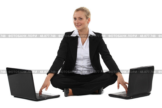 Woman sitting cross-legged in front of two computers. Стоковое фото, агентство Ingram Publishing / Фотобанк Лори