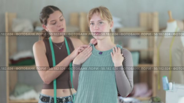Woman tailor with a client trying on a sample of a sewn dress. Female client checking the size and quality of the dress in the sewing workshop. Стоковое видео, видеограф Яков Филимонов / Фотобанк Лори