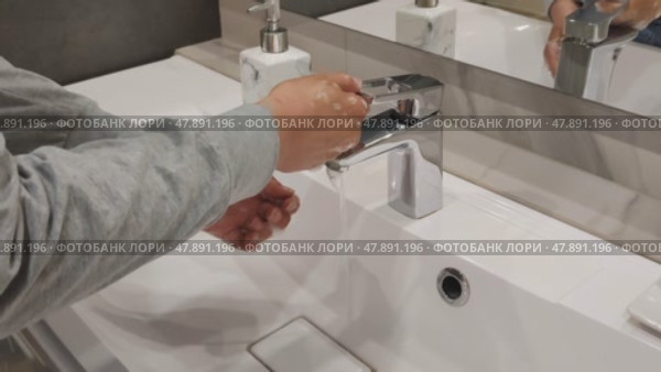 Woman turns on water in faucet and washes her hands using liquid soap. Cleanliness and hygiene of hands is key to health and prevention of infectious diseases. Стоковое видео, видеограф Ирина / Фотобанк Лори