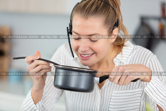 woman wearing handsfree headset spelling food in saucepan. Стоковое фото, агентство Ingram Publishing / Фотобанк Лори