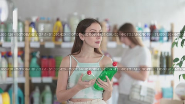 Woman went to the supermarket in the summer and chooses dishwashing detergent, she looks at the composition and environmental friendliness of the products. Visitors choose household chemicals in the store. Стоковое видео, видеограф Яков Филимонов / Фотобанк Лори