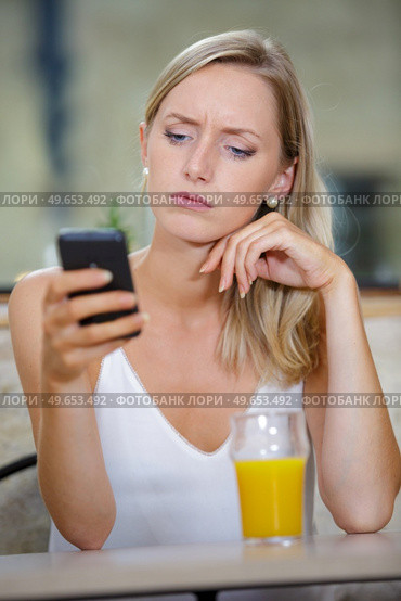 woman with dismay expression looking at her cellphone. Стоковое фото, агентство Ingram Publishing / Фотобанк Лори