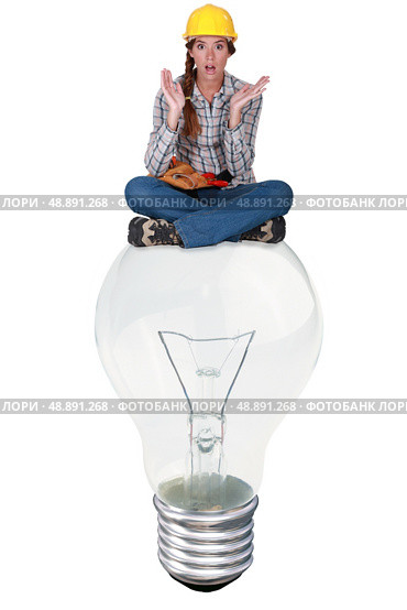 Woman with expression of surprise sat on a big light bulb. Стоковое фото, агентство Ingram Publishing / Фотобанк Лори
