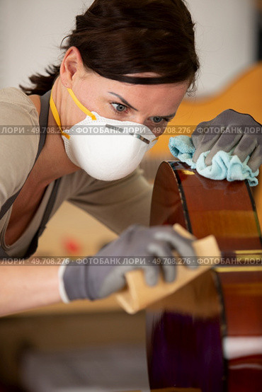 woman working as lute maker polishing classic guitar. Стоковое фото, агентство Ingram Publishing / Фотобанк Лори