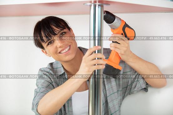 woman working on a new kitchen installation using cordless drill. Стоковое фото, агентство Ingram Publishing / Фотобанк Лори