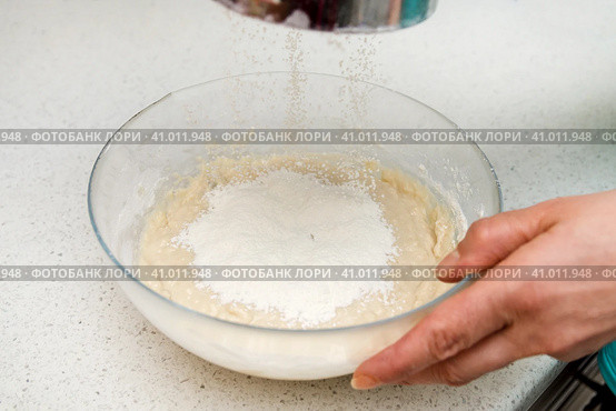 Woman's hands with an yeast dough. The woman is adding flour to the glass bowl with dough. Женские руки с дрожжевым тестом. Женщина насыпает муку в стеклянную миску с тестом. Стоковое фото, фотограф Дмитрий Березнев / Фотобанк Лори