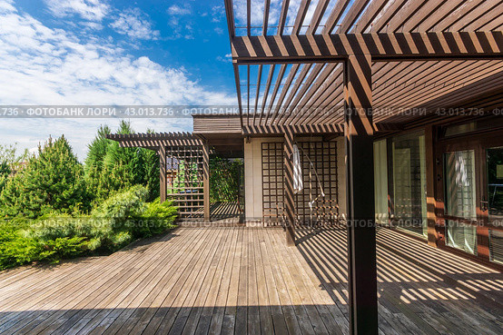 Wooden terrace with gazebo at the house on a clear sunny day. Beautiful view of the courtyard landscape. Стоковое фото, фотограф Алексей Климкин / Фотобанк Лори