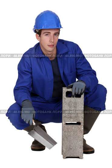 Worker holding a cinder block and trowel. Стоковое фото, агентство Ingram Publishing / Фотобанк Лори
