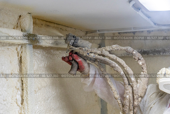 worker in a protective suit insulates the walls with polyurethane foam. Стоковое фото, фотограф Андрей Знаменский / Фотобанк Лори