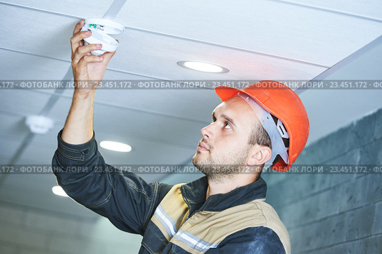 worker installing smoke detector on the ceiling. Стоковое фото, фотограф Дмитрий Калиновский / Фотобанк Лори