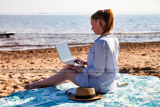 Working on a Laptop While Enjoying the Tranquility of a Sandy Beach by the Ocean Under a Bright Sun. Стоковое фото, фотограф Aleksandr Golubev / Фотобанк Лори
