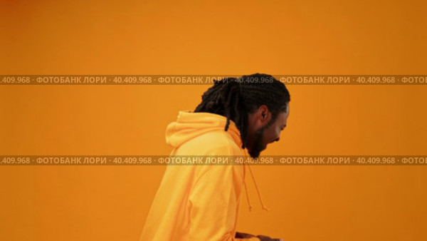 Young african guy in yellow hoodie laughing against yellow background. Стоковое видео, видеограф Сергей Толмачёв / Фотобанк Лори