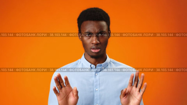 Young african man rejecting something, saying no against orange background. Стоковое видео, видеограф Сергей Толмачёв / Фотобанк Лори