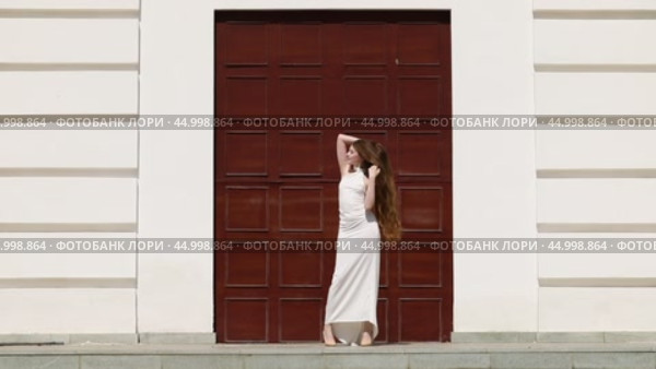 Young beautiful girl in a long white dress posing near a large gate. Стоковое видео, видеограф Андрей Аркуша / Фотобанк Лори