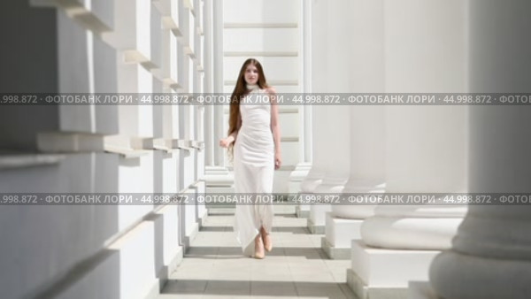 Young beautiful girl in a long white dress walks in the columned hall. Стоковое видео, видеограф Андрей Аркуша / Фотобанк Лори