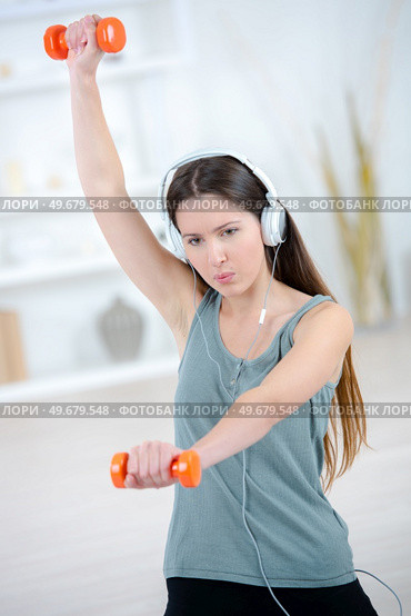 young beautiful woman in basement gym lifting weights. Стоковое фото, агентство Ingram Publishing / Фотобанк Лори