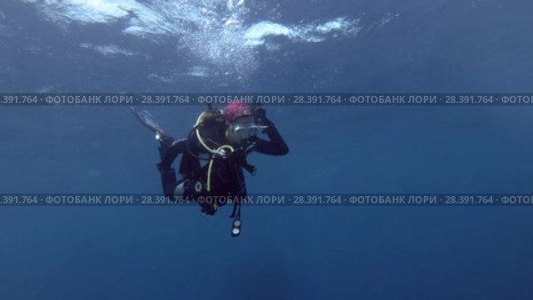 Young beautiful woman scuba diver swims in blue water under surface. Bleeds air from the BCD for immersion, Indian Ocean, Maldives (2018 год). Редакционное видео, видеограф Некрасов Андрей / Фотобанк Лори