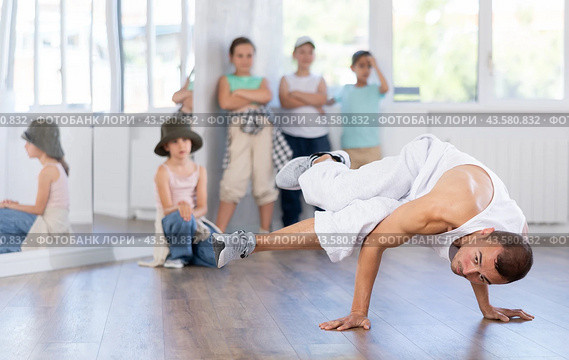 Young breakdancer demonstrating dance moves to group of tweens in studio. Стоковое фото, фотограф Яков Филимонов / Фотобанк Лори
