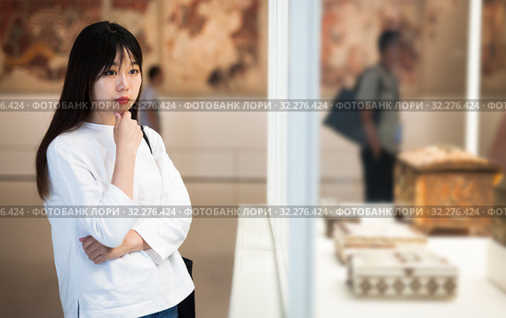 Young chinese woman visitor looking to art objects under glass. Стоковое фото, фотограф Яков Филимонов / Фотобанк Лори