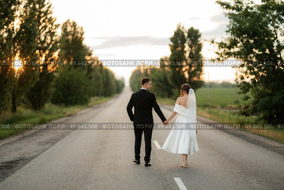 young couple bride and groom in a white short dress walking in the rain. Стоковое фото, агентство Ingram Publishing / Фотобанк Лори