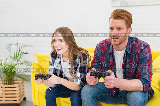 young couple having fun playing videogame home. Стоковое фото, агентство Ingram Publishing / Фотобанк Лори