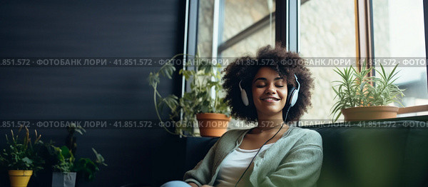 Young dark skinned women sitting near windows listening music with headphones. Banner. Copy space. Стоковое AI-изображение, AI-художник Наталья Семкина / Фотобанк Лори