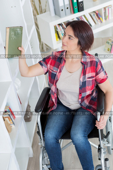 young disabled woman reaching out for blanket at shelf. Стоковое фото, агентство Ingram Publishing / Фотобанк Лори