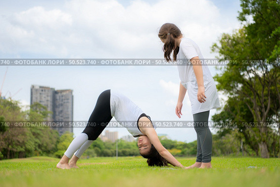 Young female and little girl with outdoor activities in the city park, Yoga is her chosen activity. Стоковое фото, агентство Ingram Publishing / Фотобанк Лори