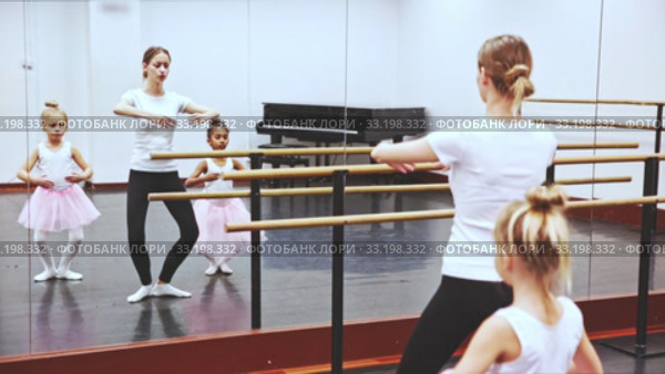 Young female ballet teacher and two little girls in classical dance school. Стоковое видео, видеограф Яков Филимонов / Фотобанк Лори