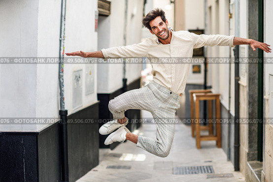 Young funny man jumping in the street. Attractive Guy wearing casual clothes in urban background. Male taking a great leap.. Young funny man jumping in the street. Стоковое фото, агентство Ingram Publishing / Фотобанк Лори