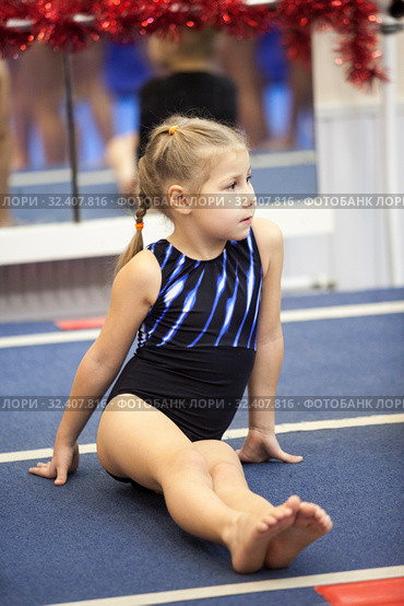 Young gymnast sitting on gymnastic platform, four years old girl engages in sport school. Стоковое фото, фотограф Кекяляйнен Андрей / Фотобанк Лори