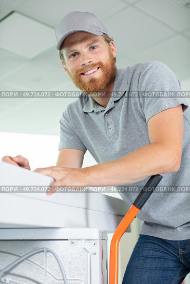 young happy man carrying washer. Стоковое фото, агентство Ingram Publishing / Фотобанк Лори
