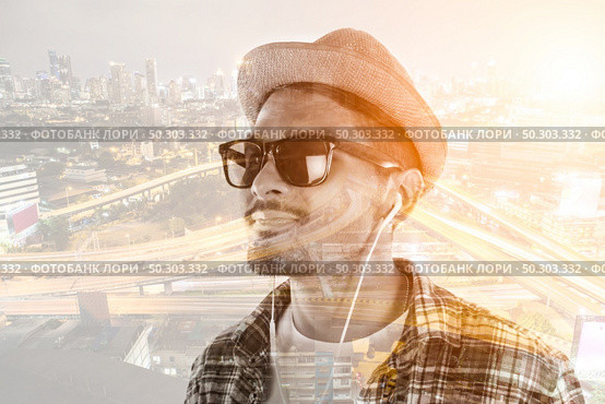 Young hipster man in earphones holding smartphone isolated on the white background. Стоковое фото, агентство Ingram Publishing / Фотобанк Лори