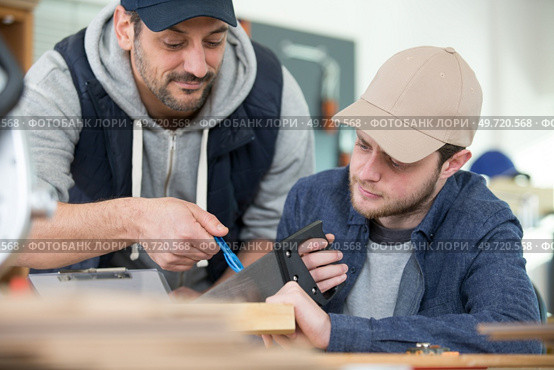 young male apprentice using saw under supervision. Стоковое фото, агентство Ingram Publishing / Фотобанк Лори