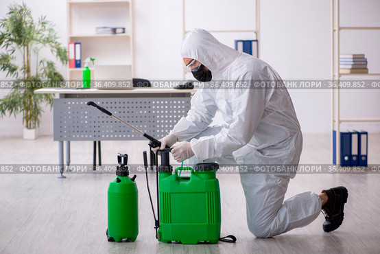 Young male contractor disinfecting office during pandemic. Стоковое фото, фотограф Elnur / Фотобанк Лори