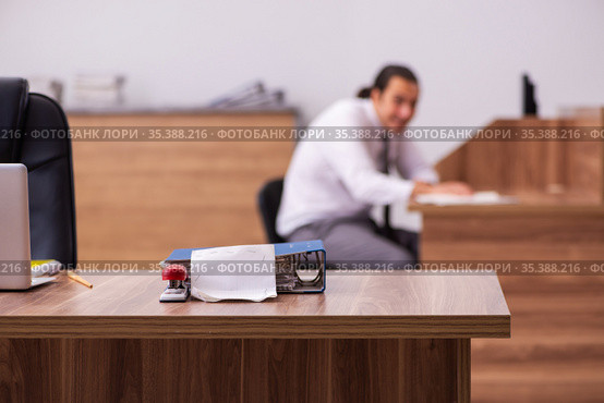 Young male employee stapling paper in the office. Стоковое фото, фотограф Elnur / Фотобанк Лори