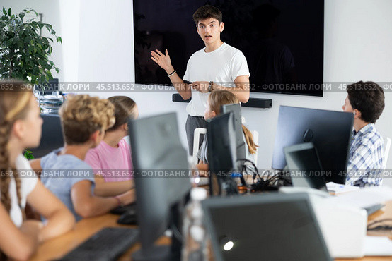 Young male teacher speaking to underage attendees of computer courses. Стоковое фото, фотограф Яков Филимонов / Фотобанк Лори