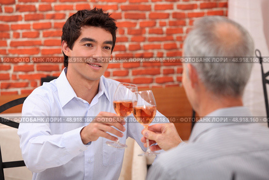 Young man and senior chinking wine glasses. Стоковое фото, агентство Ingram Publishing / Фотобанк Лори