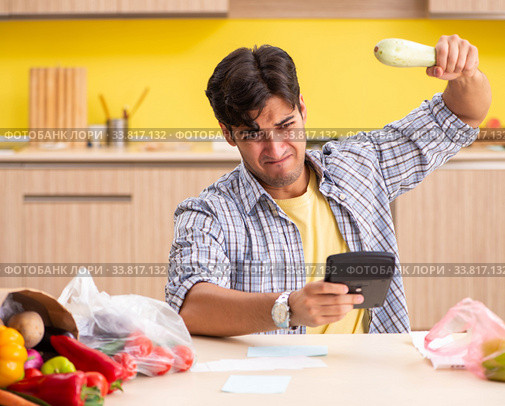 Young man calculating expences for vegetables in kitchen. Стоковое фото, фотограф Elnur / Фотобанк Лори