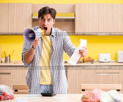 Young man calculating expences for vegetables in kitchen. Стоковое фото, фотограф Elnur / Фотобанк Лори